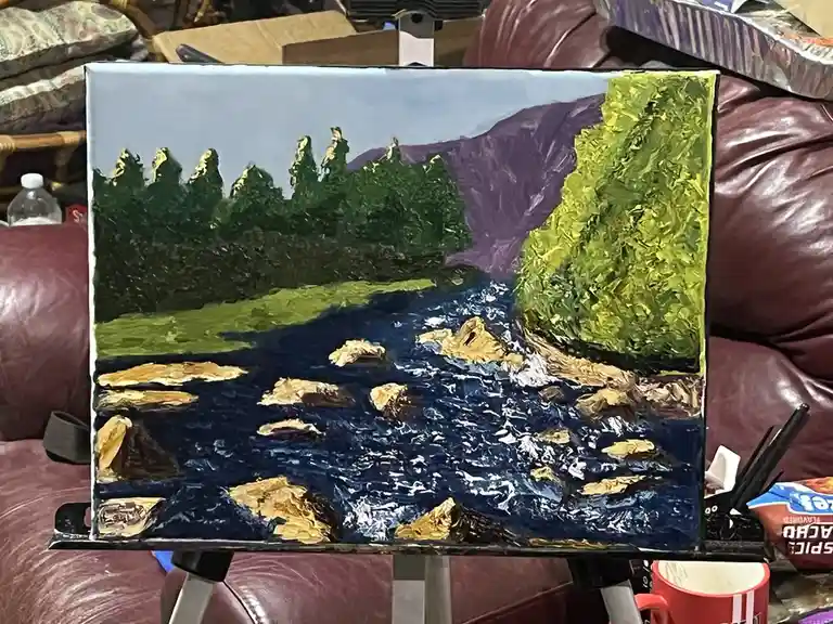 A thickly textured painting of a river scene with green trees, purple mountains, and dark blue water with rocks, displayed…