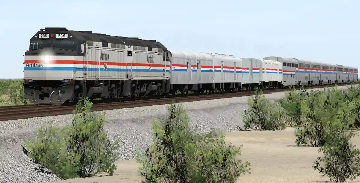 An Amtrak passenger train, locomotive number 295, travels through a dry, scrubby landscape with sparse bushes and gravel…