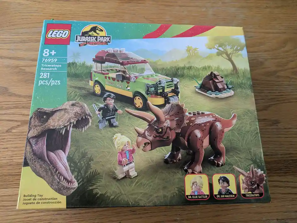 The image shows the front of a LEGO Jurassic Park 30th Anniversary set box (76959, Triceratops Research) featuring a green…