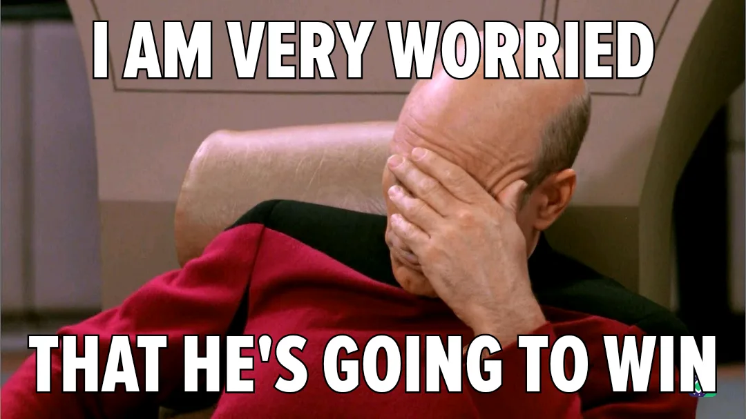 A bald man in a red uniform sits in a chair, covering his face with his hand in a gesture of despair or frustration. The…