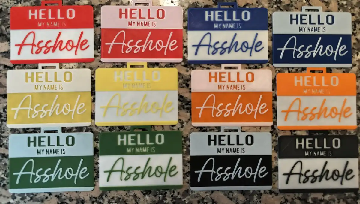 Ten name tags arranged in three rows on a speckled countertop, each featuring the standard 'HELLO MY NAME IS' header…