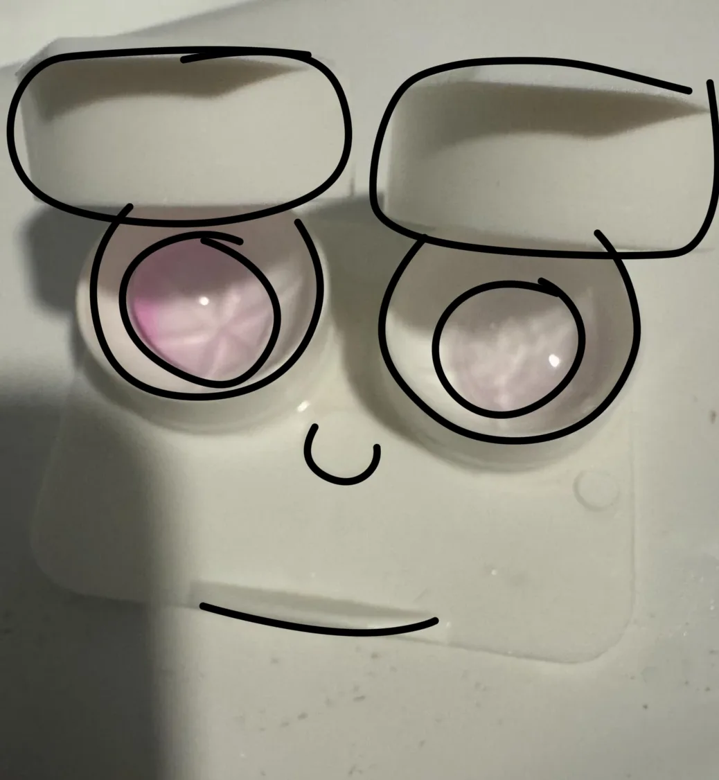 A close-up photo of two contact lens cases, one containing a pink lens and the other a clear lens, with a simple hand-drawn…