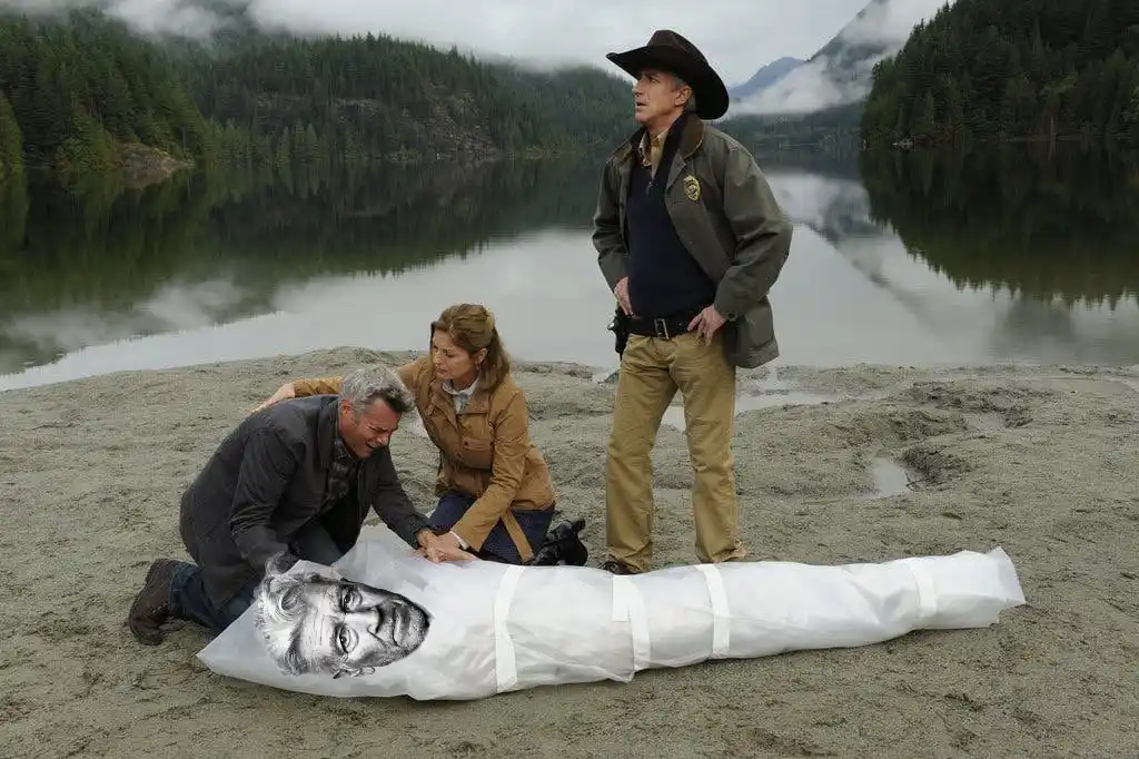 Three people stand on a misty lakeshore; two kneel beside a white body bag lying on sand, while a man in a cowboy hat stands…