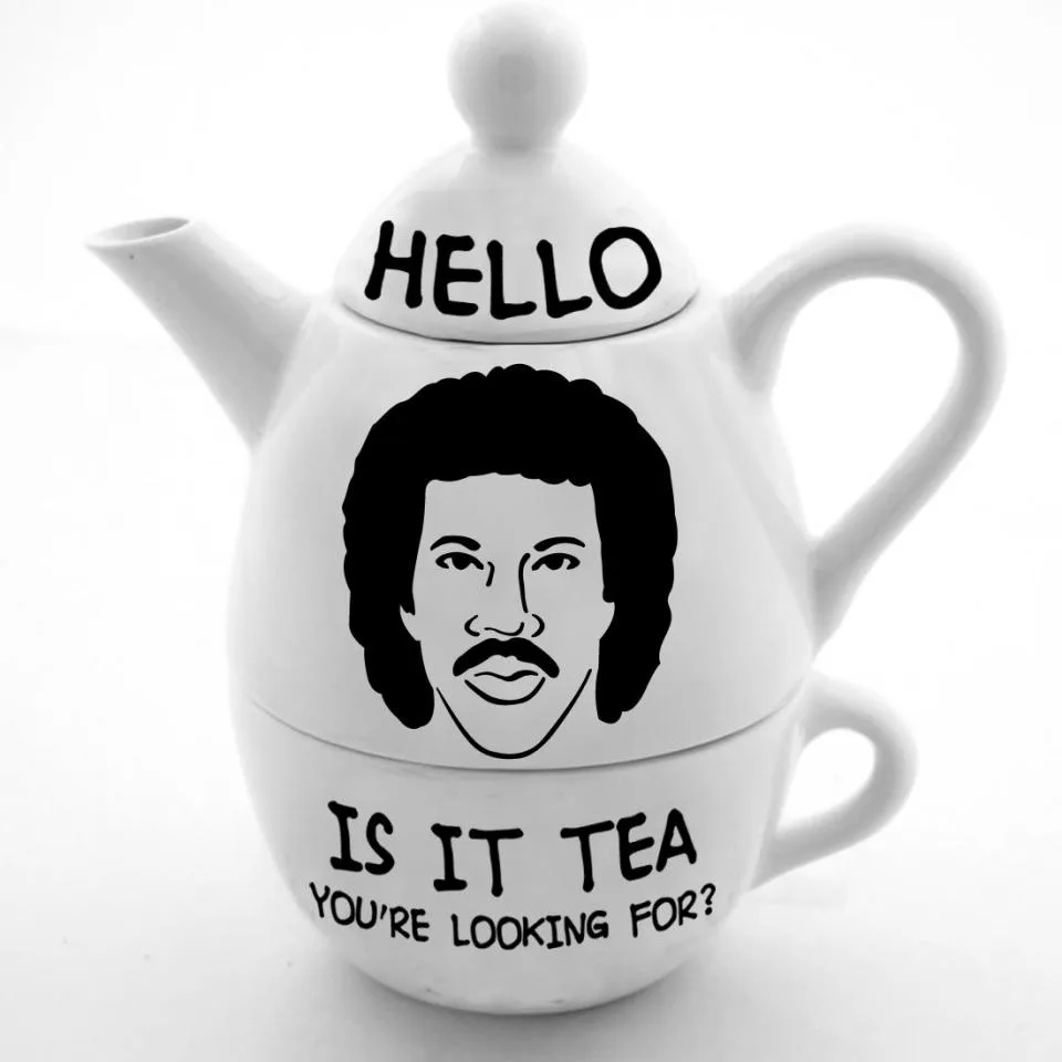 A white ceramic teapot with a lid, handle, and spout, featuring a black-and-white line drawing of a man with an afro and…