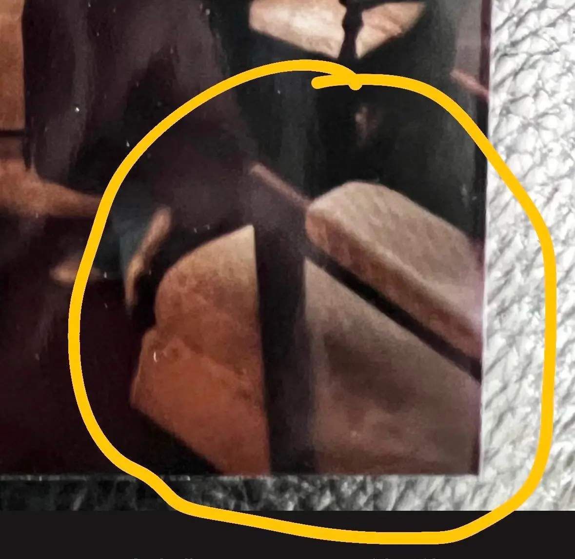 A close-up of a blurry, low-resolution image of what appears to be a wooden chair or bench with a dark vertical support…