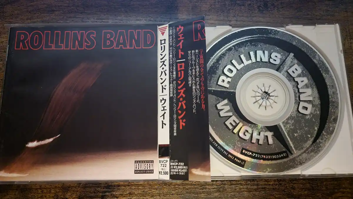 A Japanese CD case for the album 'Weight' by Rollins Band, showing the cover art with a brown streak against a dark…