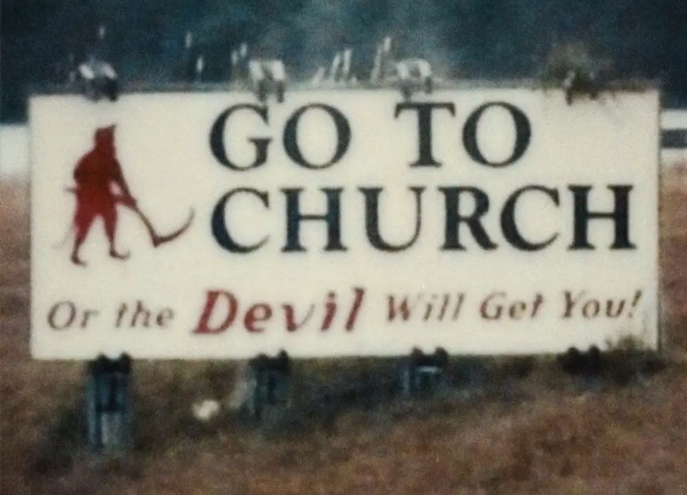 A weathered roadside sign urges viewers to 'GO TO CHURCH' in large black letters, with smaller red text below reading 'Or…
