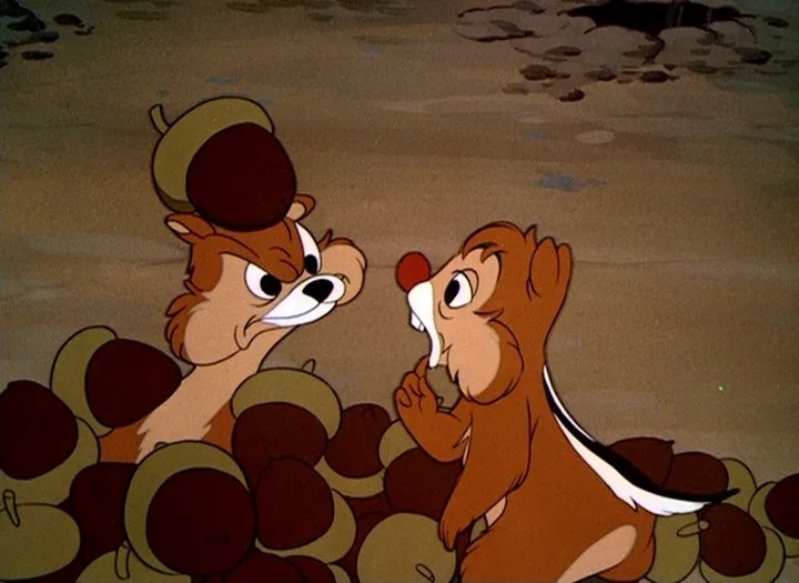 Two cartoon chipmunks, Chip and Dale, are surrounded by acorns. Chip looks angry and sternly at Dale, who looks guilty and…