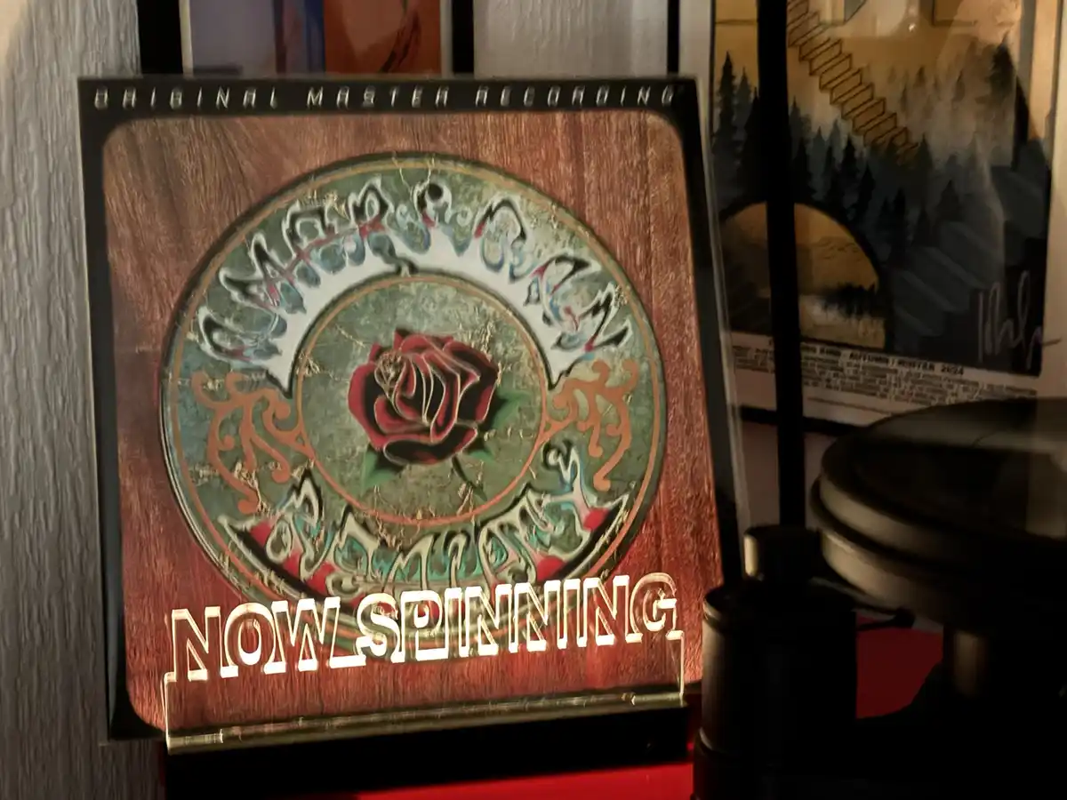 A close-up of a vinyl record album cover featuring a red rose in the center, surrounded by ornate, swirling patterns on a…