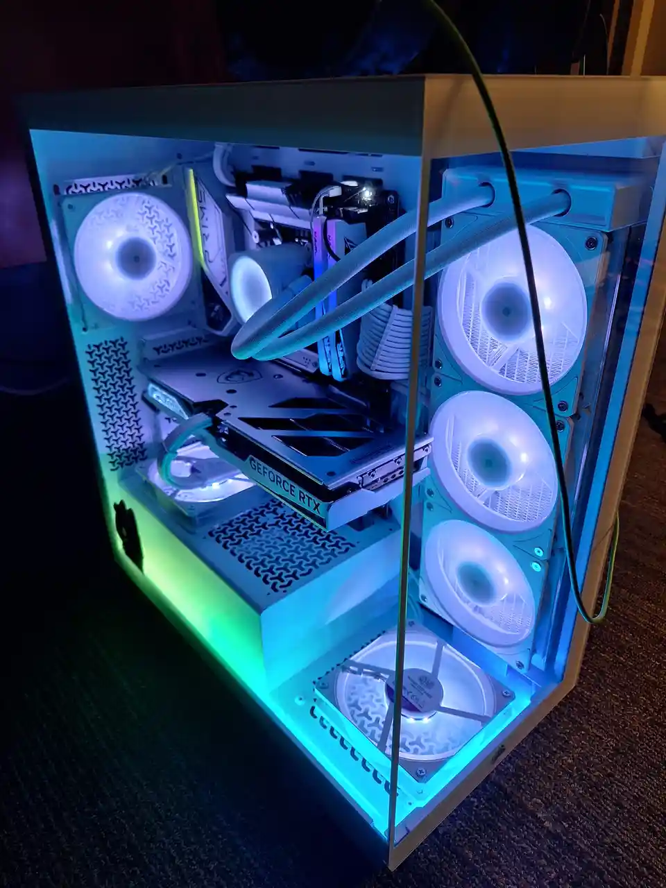 A custom-built gaming PC with a transparent side panel, showcasing multiple glowing white fans, a GeForce RTX graphics card…