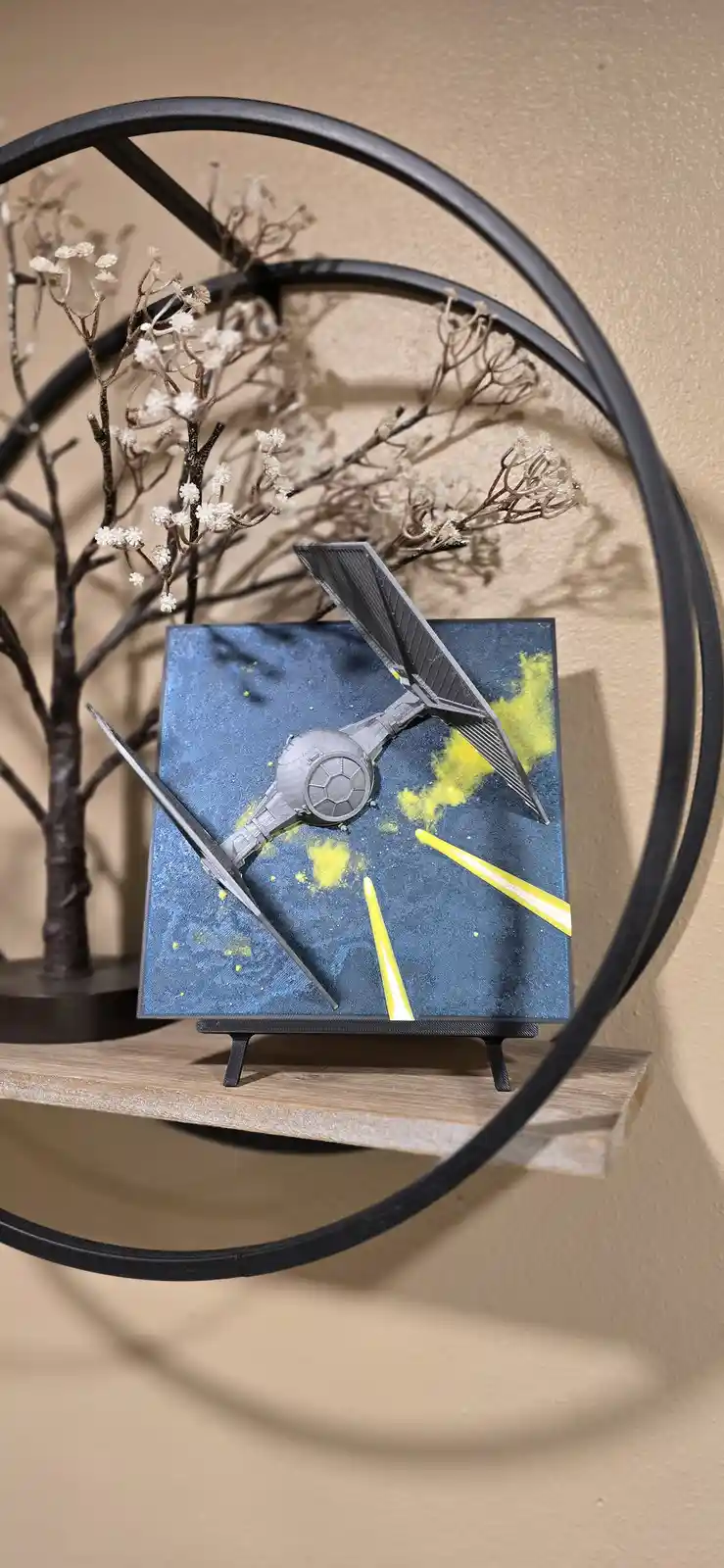 A decorative clock with a Star Wars TIE fighter as its hour hand and a yellow light saber as its minute hand, set against a…