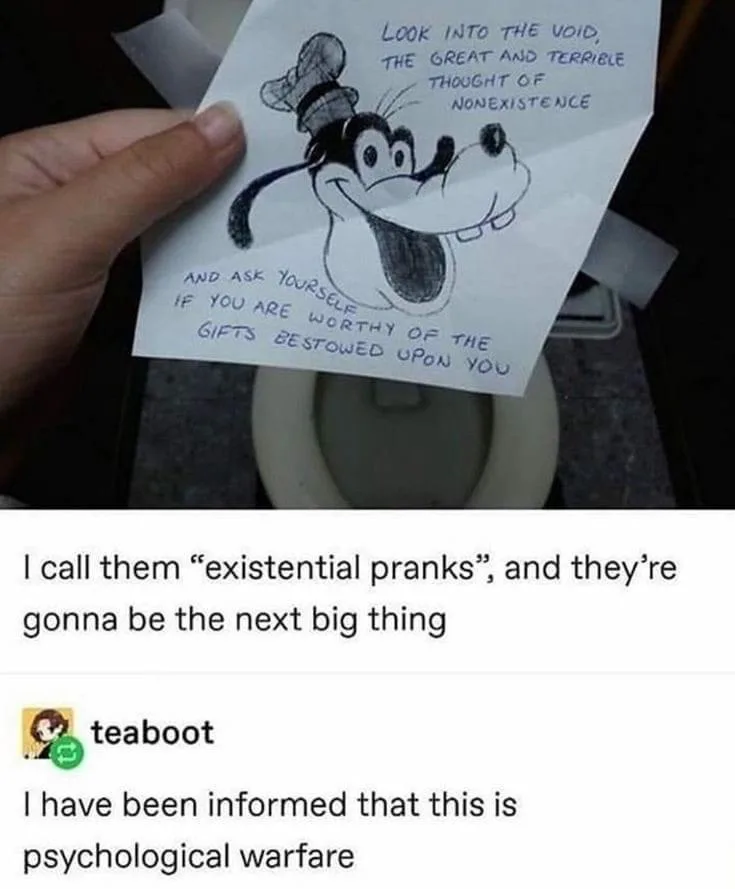 A hand holds a hand-drawn cartoon of Goofy with a chef's hat, taped over a toilet bowl. The drawing has handwritten text…