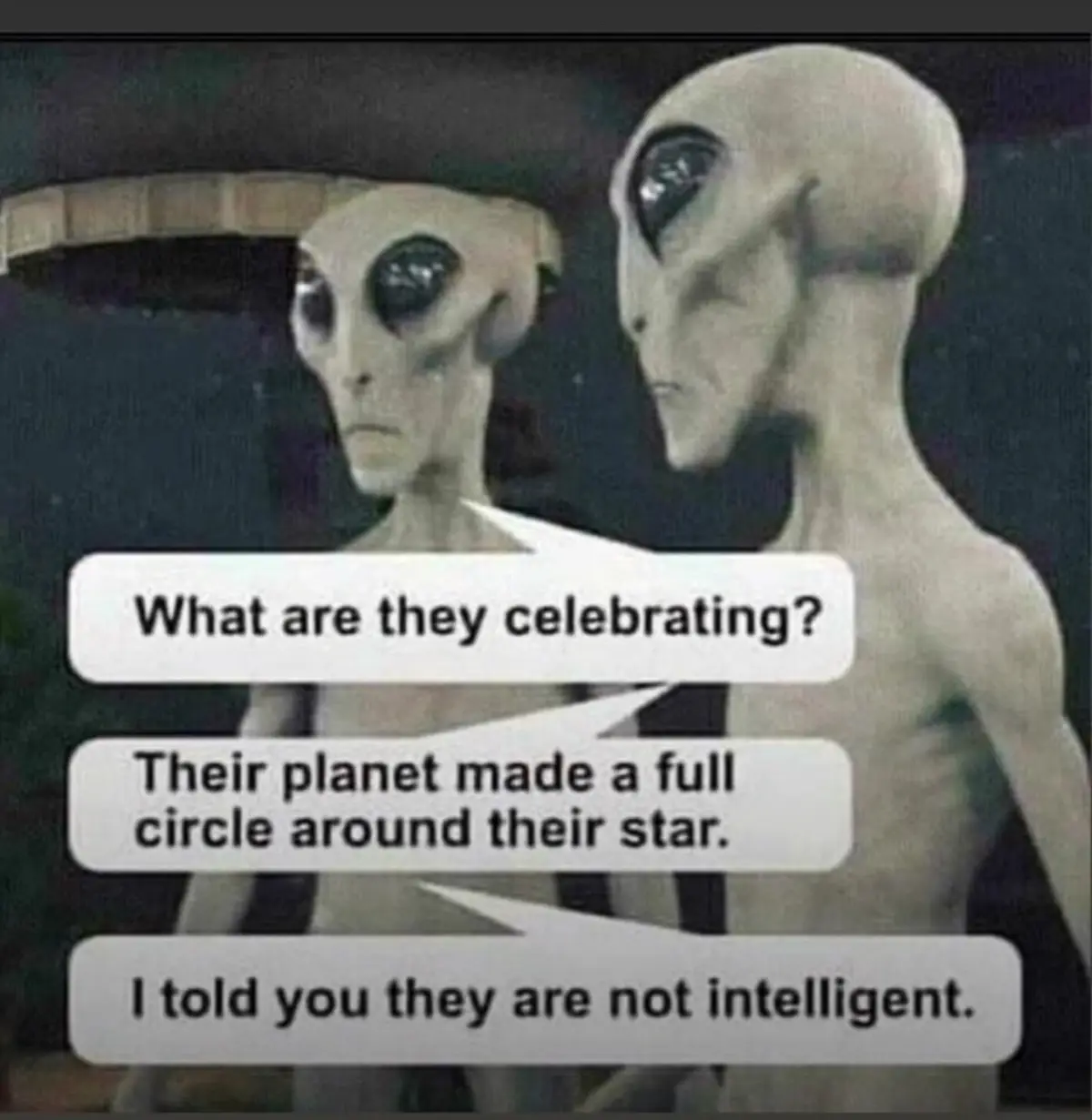 Two grey aliens with large black eyes are shown in profile, one facing forward and the other turned slightly away. Three…