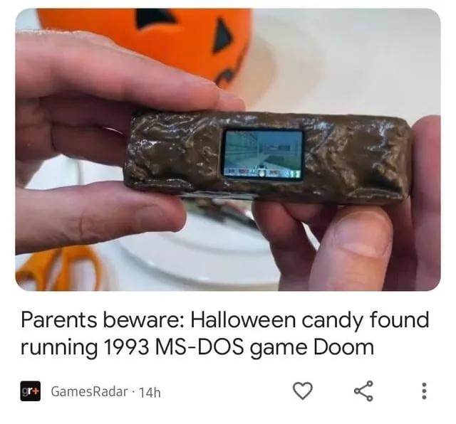 A pair of hands holds a small, rectangular object covered in brown, textured candy coating, resembling a chocolate bar. A…