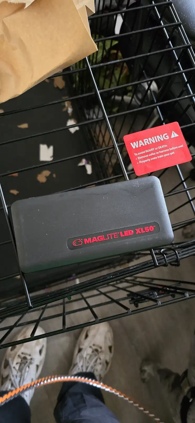 A black Maglite LED XL50 flashlight sits in a black wire pet crate, next to a red warning label that reads 'WARNING To avoid…