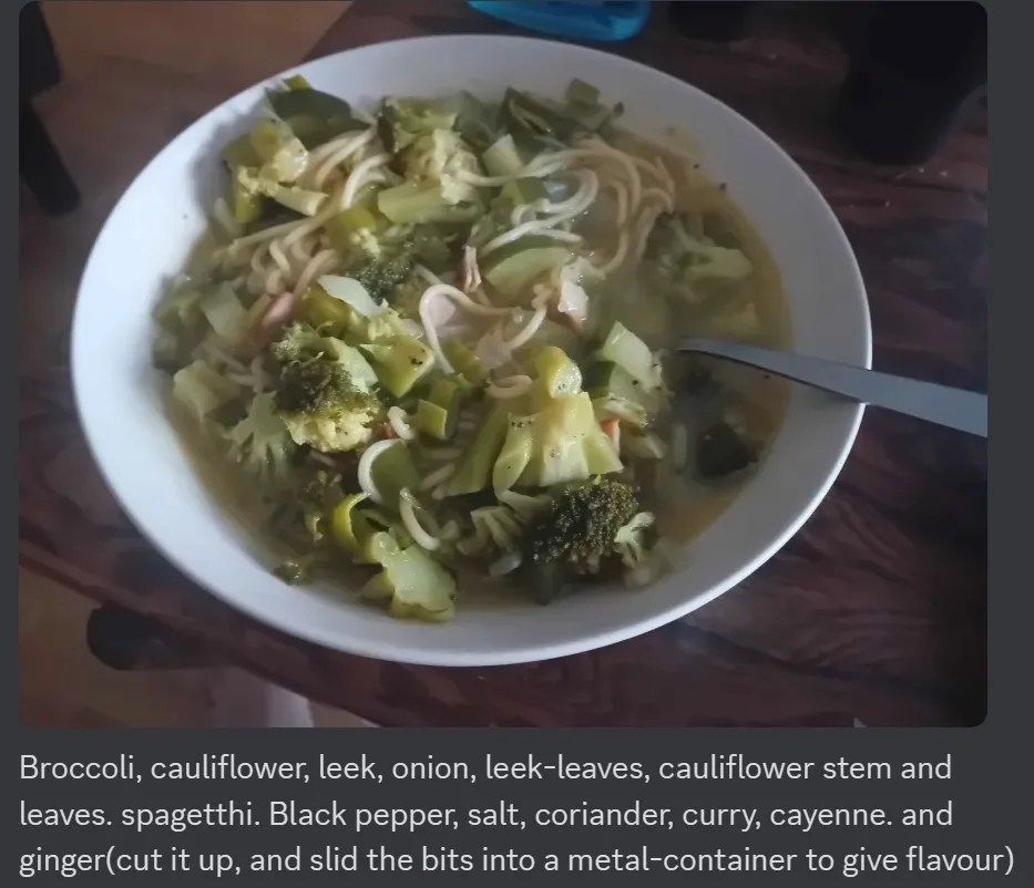 A white bowl filled with a soup-like dish containing visible pieces of broccoli, cauliflower, leek, onion, and spaghetti…