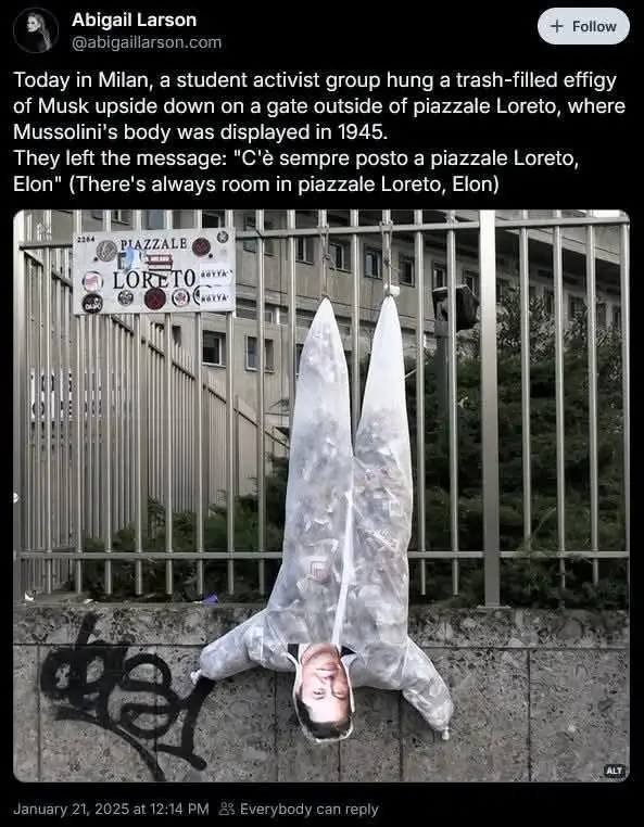 An upside-down effigy of Elon Musk, made from a clear plastic bag filled with trash, hangs from a metal fence. The head is…