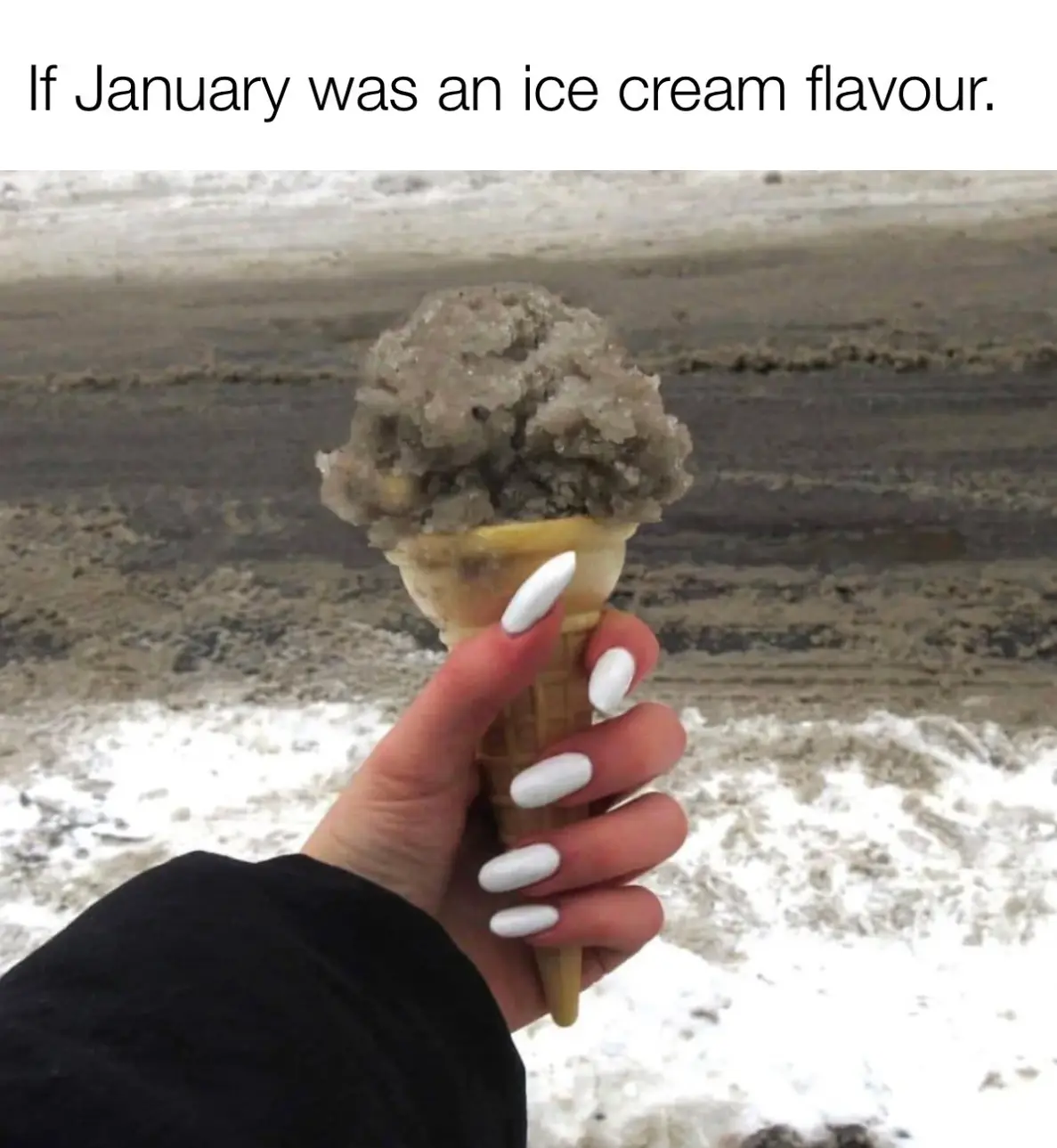 A hand with white manicured nails holds an ice cream cone with a scoop that looks like dirty snow or slush, set against a…
