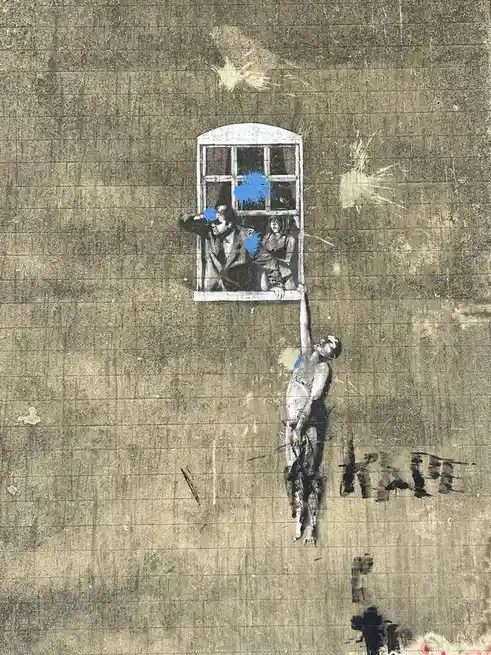 A gritty, textured artwork depicts a nude figure hanging from a window ledge, while two people peer out the window above…