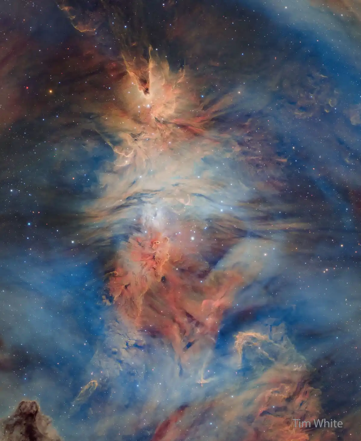 A stunning astrophotograph of a colorful nebula with swirling clouds of gas in shades of blue, orange, and red, dotted with…