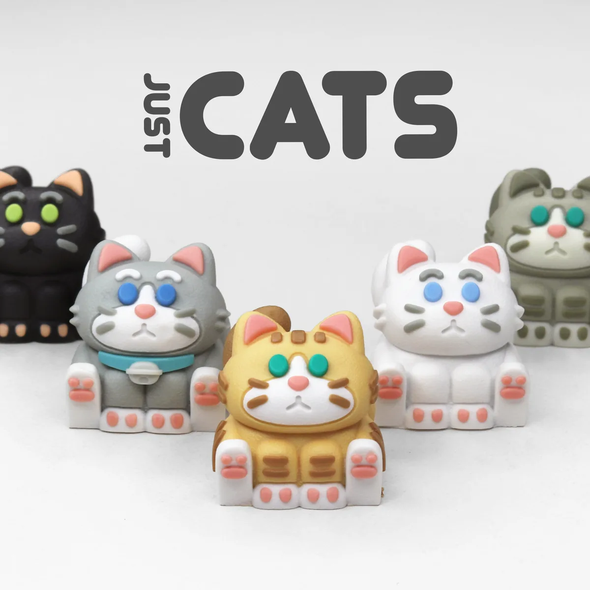 Five stylized, colorful cat figurines with distinct fur patterns and eye colors are arranged in a row against a plain white…
