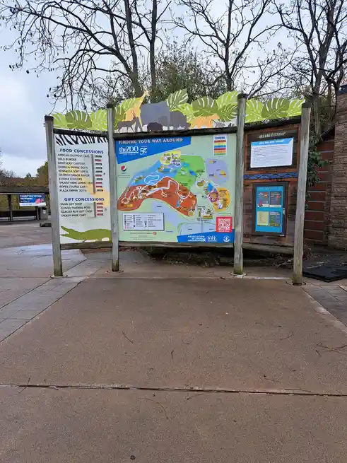 A large outdoor zoo map sign for 'theZOO' shows a detailed layout with colored zones, food concessions, and gift shops. The…