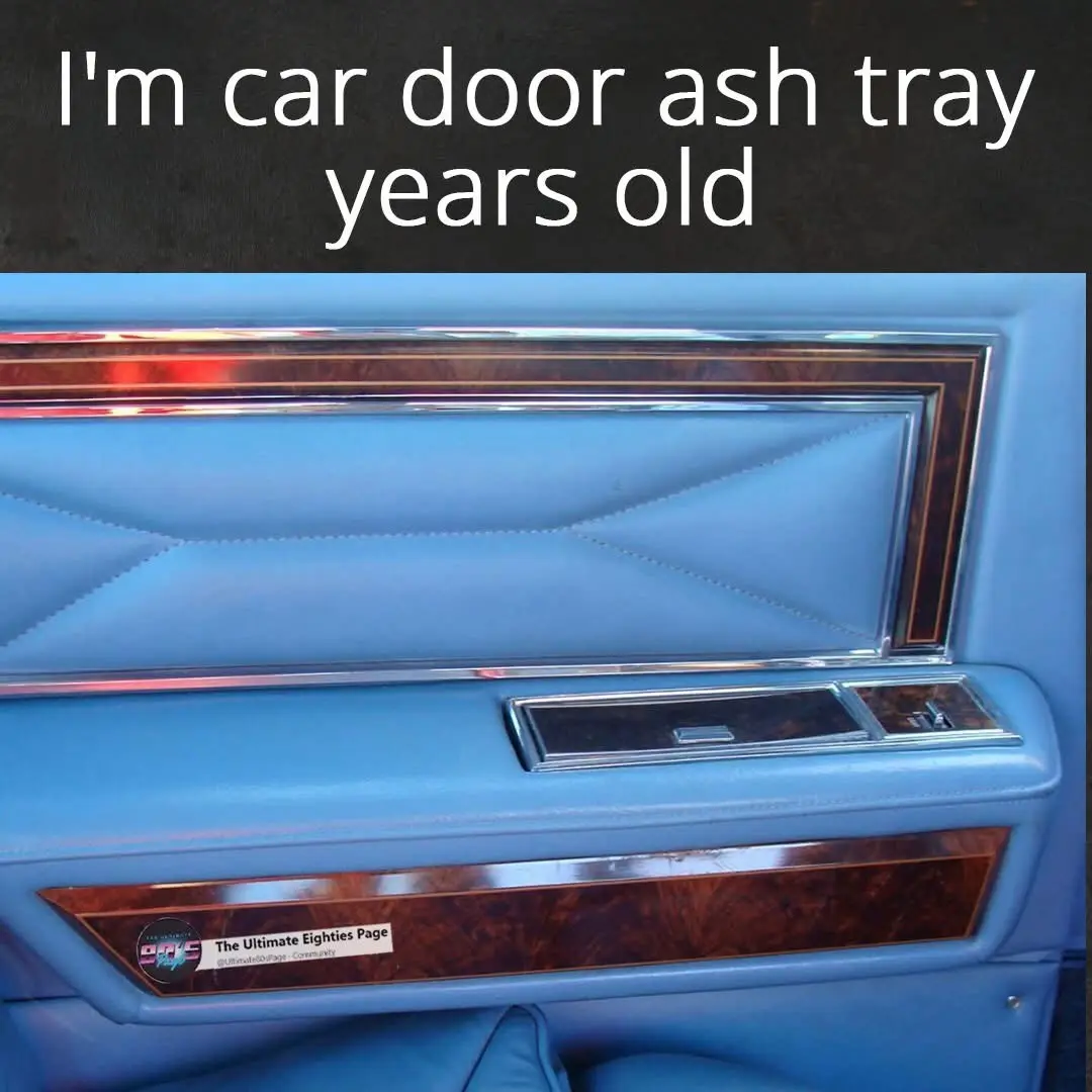 A close-up photo of a vintage car's blue leather door panel with wood trim and chrome accents, featuring a built-in ashtray…