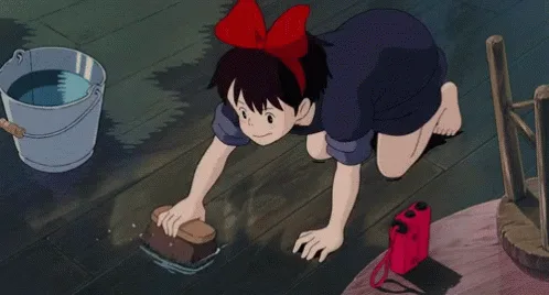 A sequence of six frames from the anime 'Kiki's Delivery Service' shows the young witch Kiki kneeling and scrubbing a wooden…
