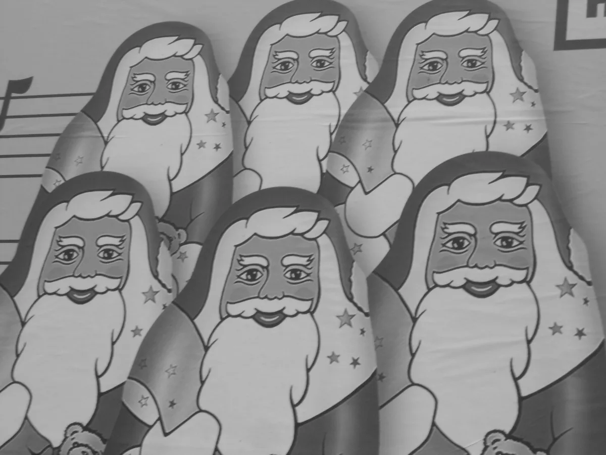 A black-and-white image shows multiple identical cartoon depictions of Santa Claus arranged in a repeating pattern on a…