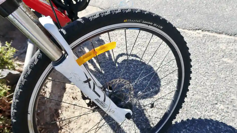 A close-up photo of a bicycle's front wheel and fork, showing a black tire with the brand name 'Chaptah' and model 'Lascivio…