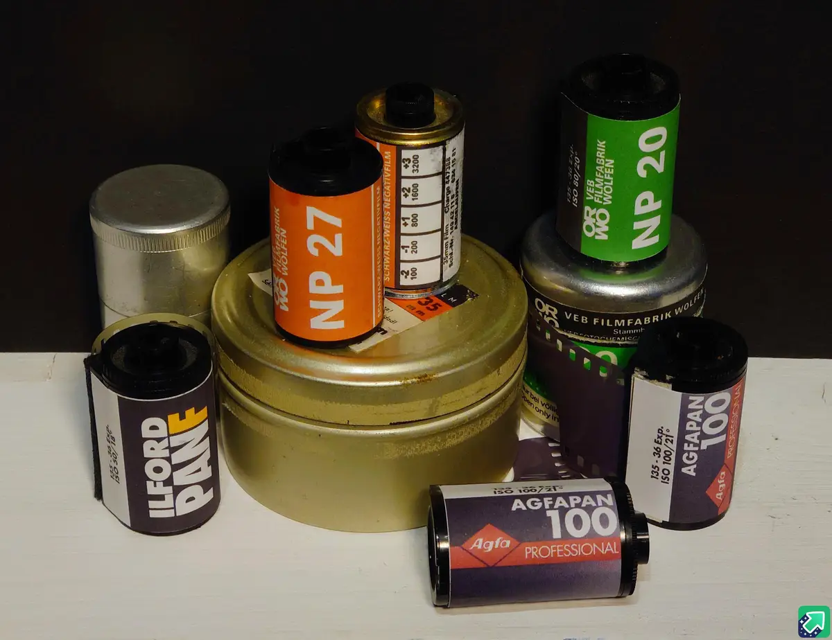 A collection of vintage film rolls, including Ilford P400, Agfa 100, and VEB Filmfabrik Wolfen NP 20 and NP 27, arranged on…