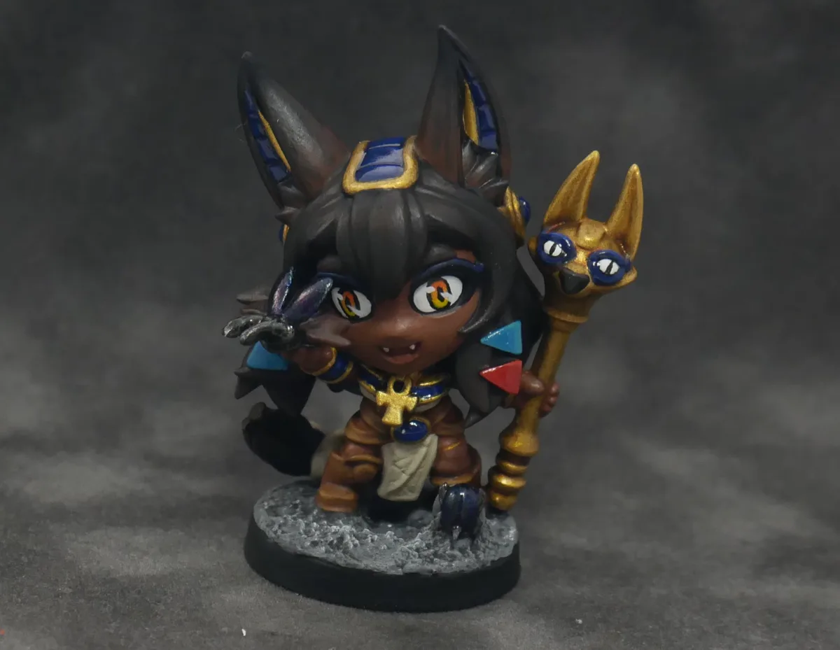 A hand-painted miniature figurine of a chibi-style anthropomorphic canine character with large pointed ears, holding a…