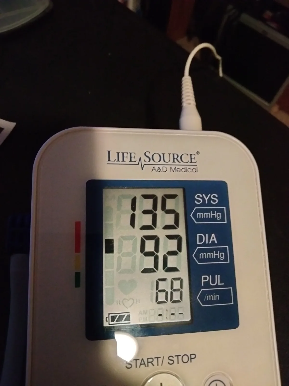 A close-up of a white LifeSource A&D Medical blood pressure monitor displaying a reading of 135/92 mmHg systolic/diastolic…