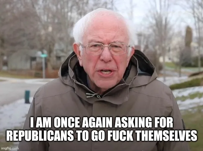 A close-up photo of Bernie Sanders, an older man with white hair and glasses, wearing a brown hooded jacket outdoors in a…