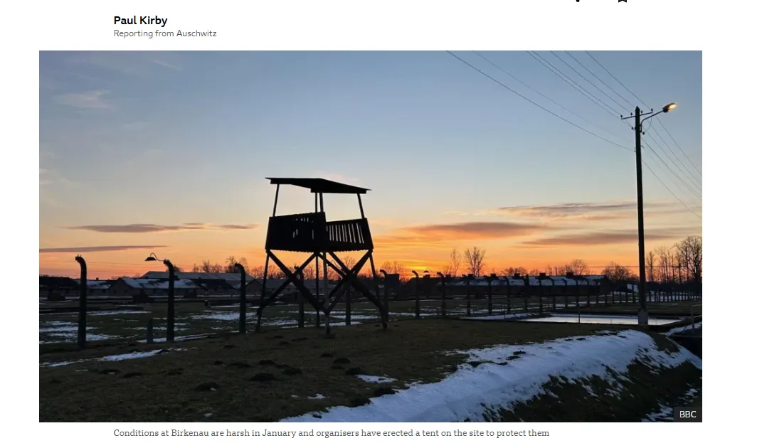 A silhouette of a watchtower at a former concentration camp at sunset, with barbed wire fences and snow patches visible. The…