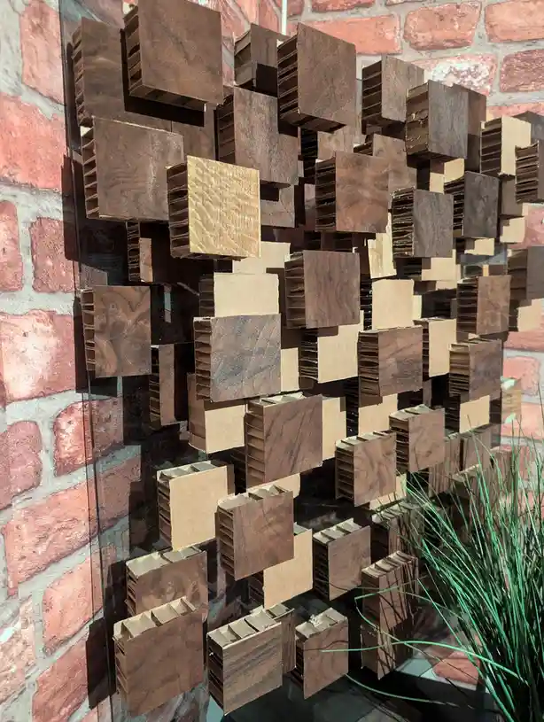 a close-up of a decorative wall art piece made of many small, square, corrugated cardboard pieces with wood grain patterns…