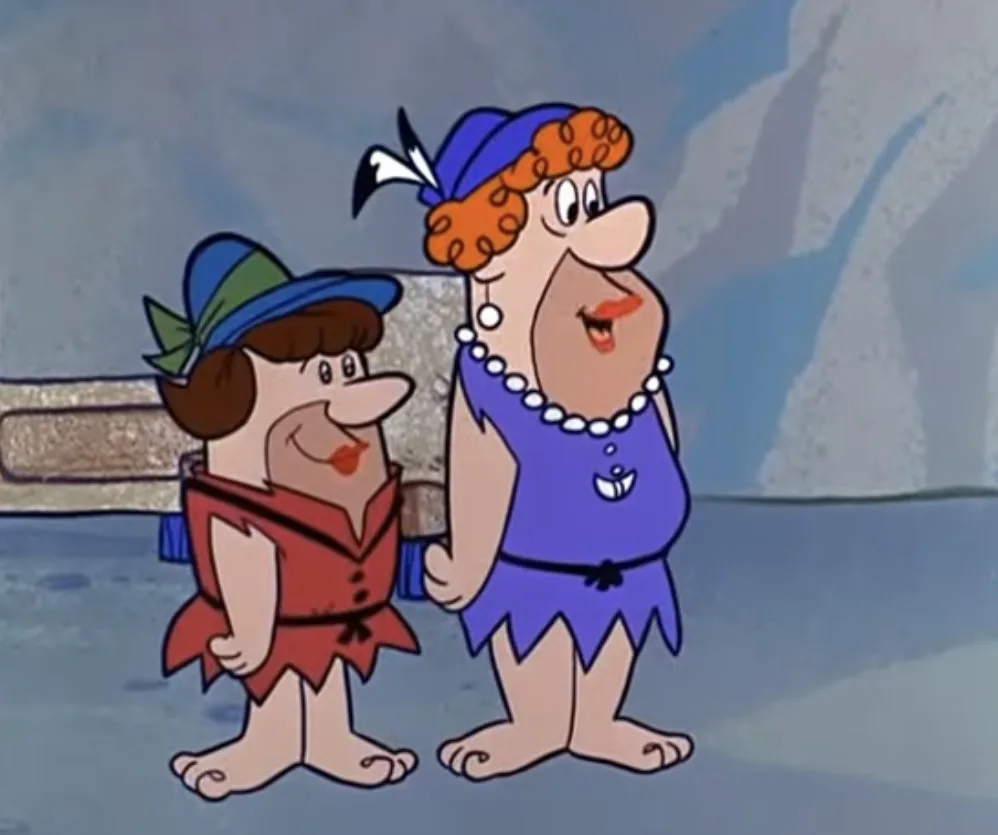 Two cartoon characters from 'The Flintstones' stand side by side; the taller one, wearing a blue dress and pearl necklace…