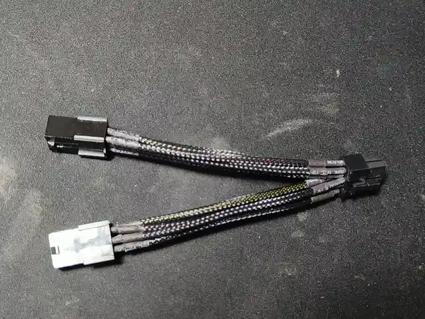 The image shows two computer power cables lying on a dark gray fabric surface. One cable has a black connector, the other…