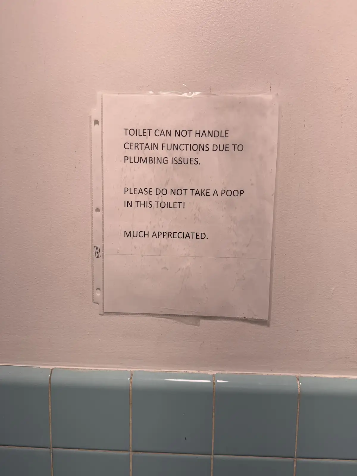 A printed sign taped to a wall above blue tiles in a restroom humorously warns users not to use the toilet for 'certain…