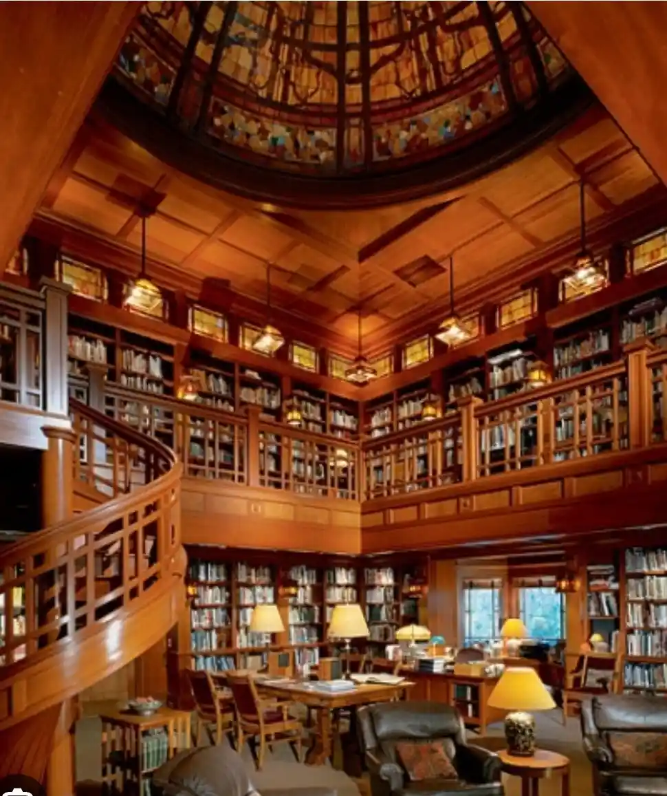 An ornate, multi-level wooden library with stained-glass dome ceiling, spiral staircase, and bookshelves lining every wall…