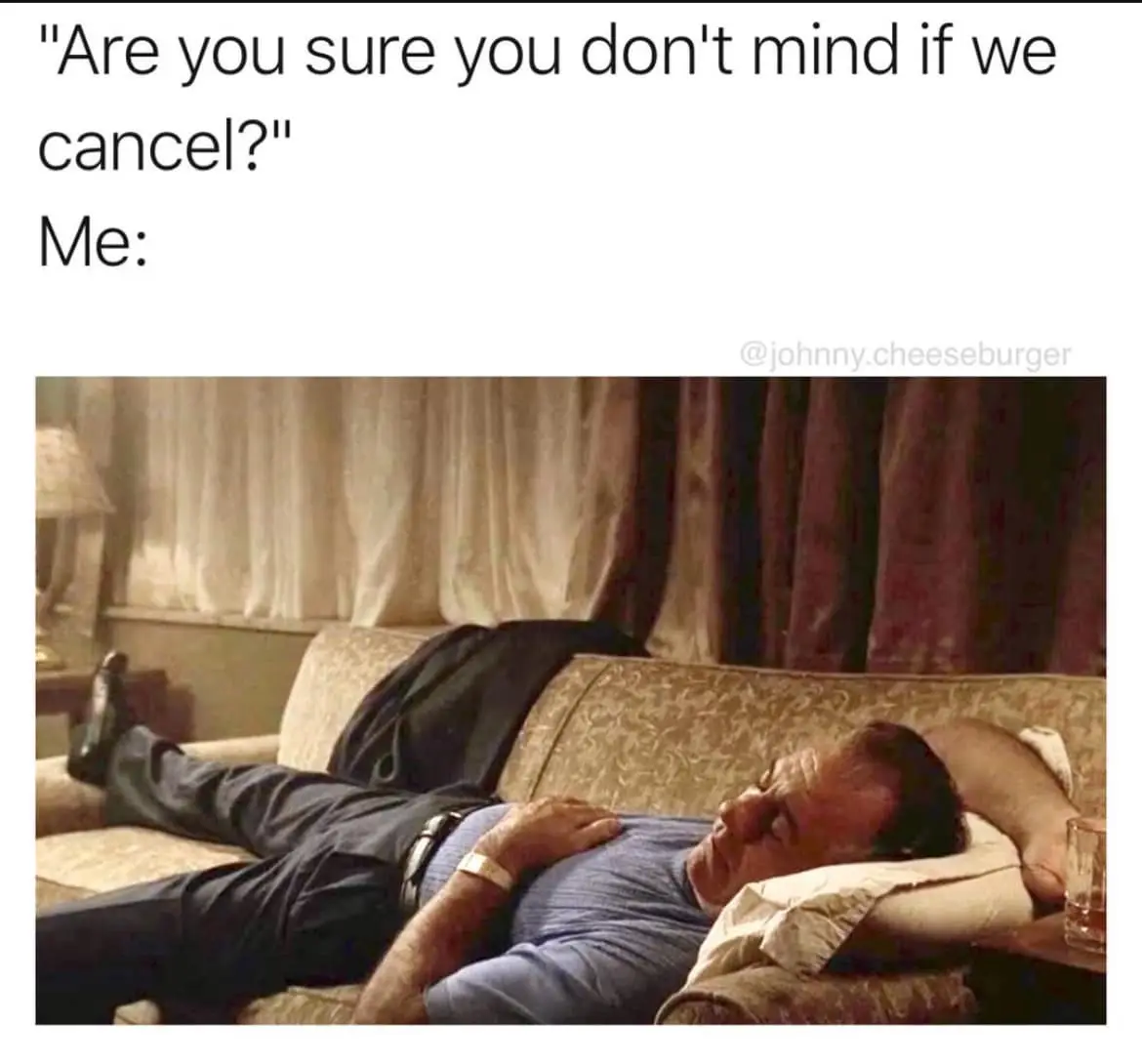 A man is lying on a couch, appearing deeply asleep or exhausted, with one arm under his head and the other resting on his…