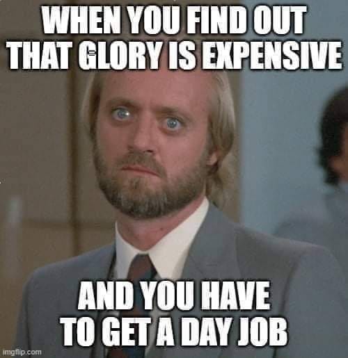 A man with blonde hair, a beard, and wide blue eyes stares with a shocked and dismayed expression while wearing a suit and…