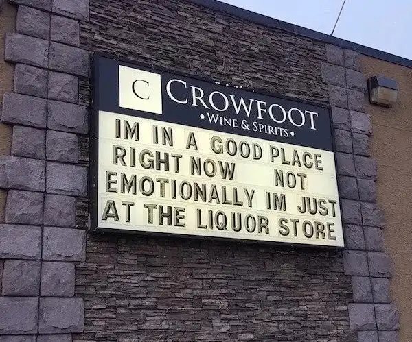 A photo of a liquor store sign for 'Crowfoot Wine & Spirits' with a marquee that reads 'IM IN A GOOD PLACE RIGHT NOW NOT…