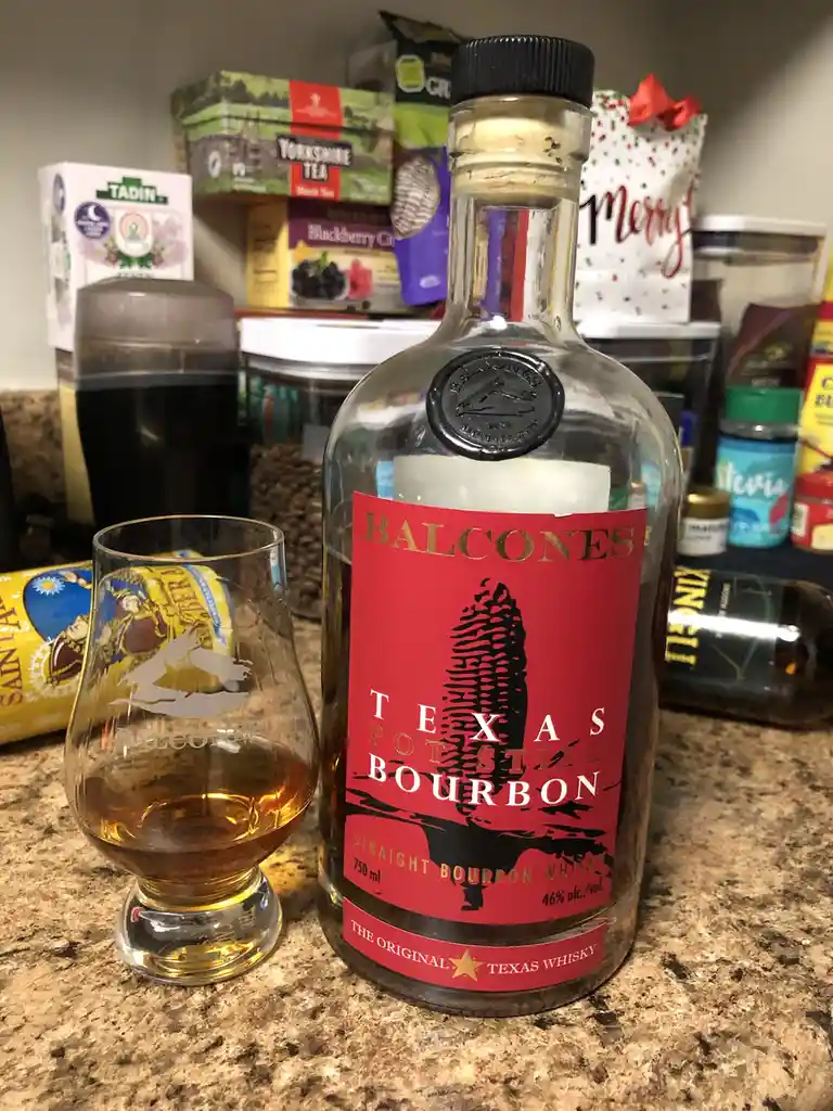A bottle of Balcones Texas Pot Still Bourbon whiskey and a tasting glass with a small amount of amber liquid sit on a…