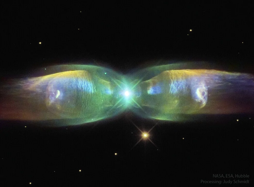 A Hubble Space Telescope image of a planetary nebula with two symmetrical, glowing lobes resembling eyes, set against a…