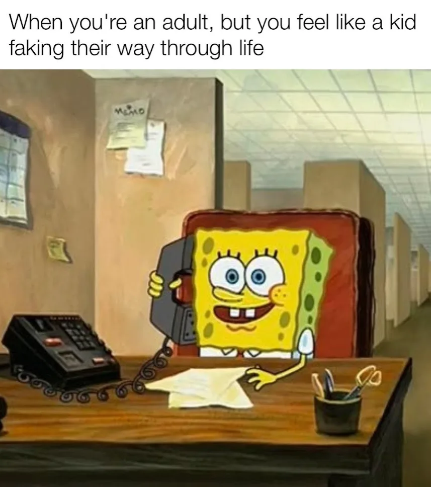 SpongeBob SquarePants sits at a wooden office desk in a cubicle, holding a black telephone receiver to his ear with a wide…