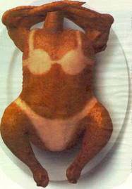 A roasted chicken is shown lying on its back on a white plate, with its wings raised above its head and its legs bent at the…