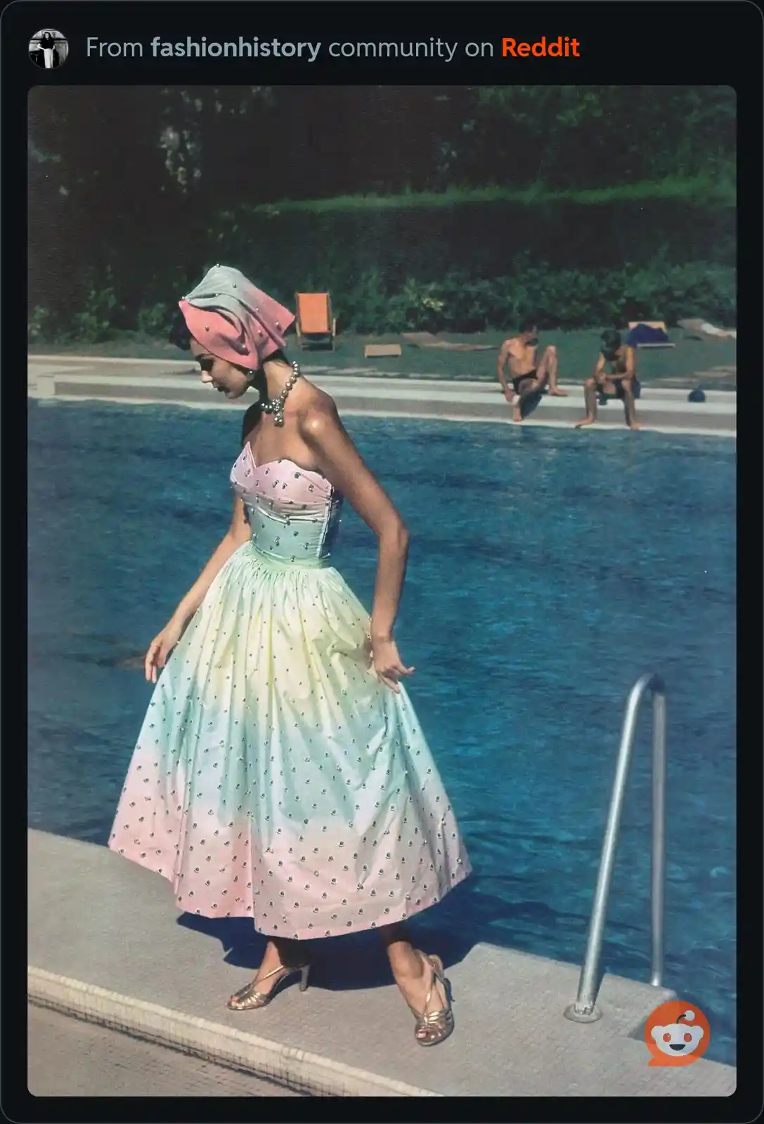 A woman in a vintage, strapless, pastel ombre dress with a pink and blue gradient and silver embellishments walks away from…