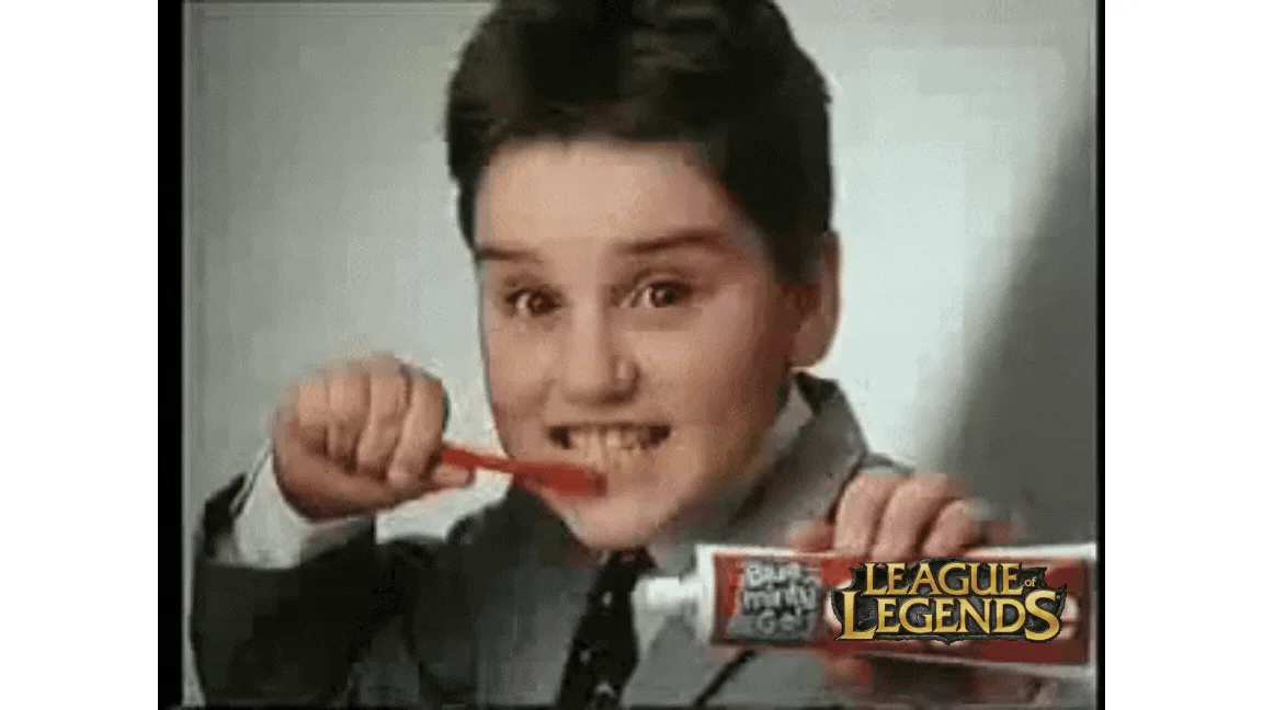 A young boy in a suit brushes his teeth with a red toothbrush while holding a tube labeled 'League of Legends'. The image is…