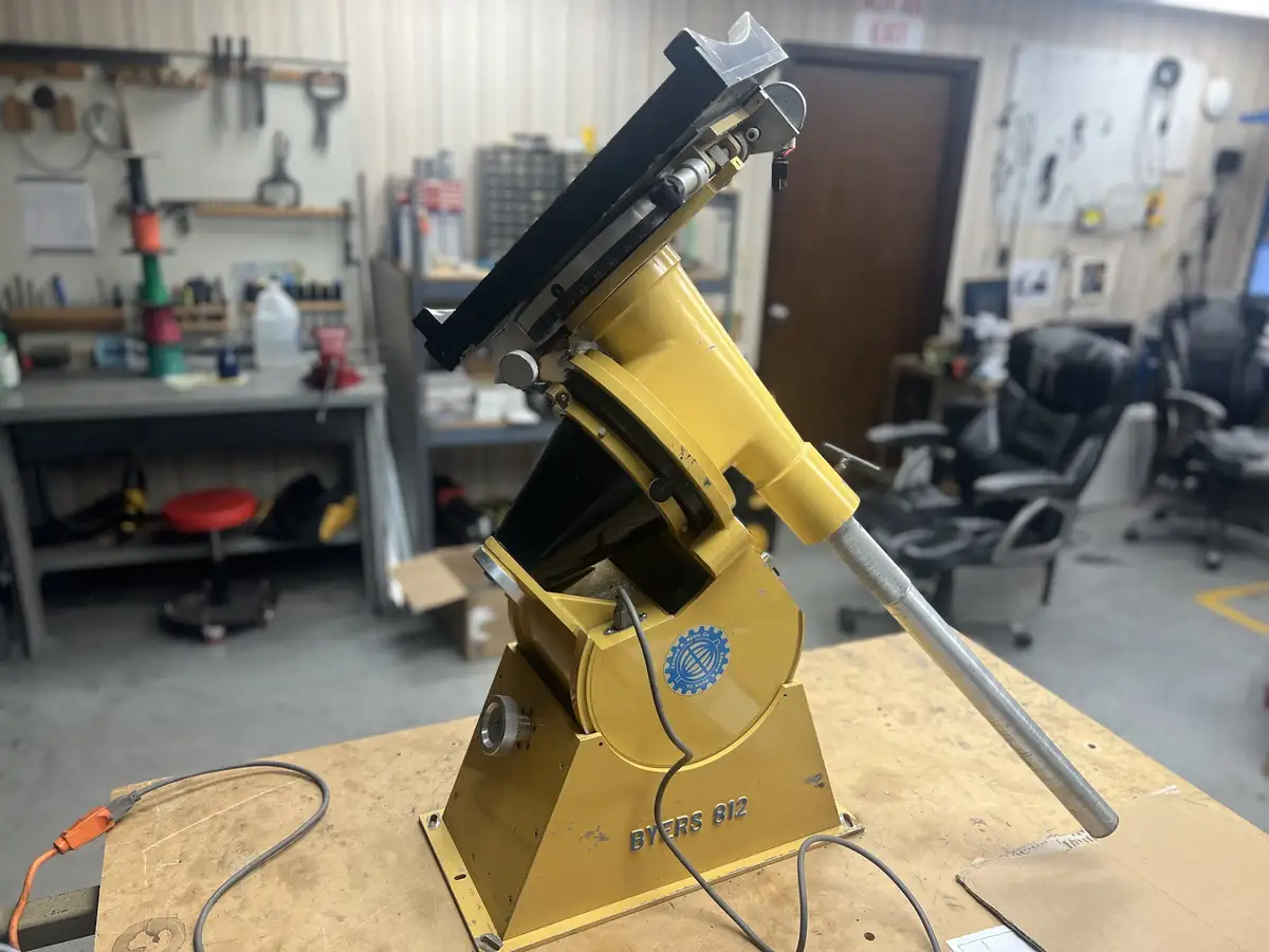 A yellow Byers 812 industrial machine, likely a drill press or similar tool, sits on a wooden workbench in a cluttered…